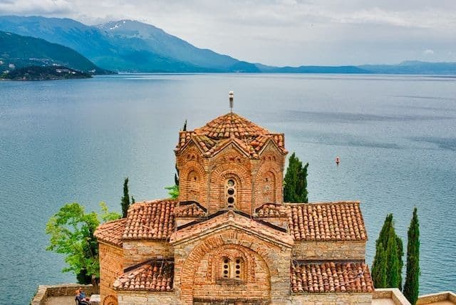 Photo of a monastery in front of a lake and mountains
